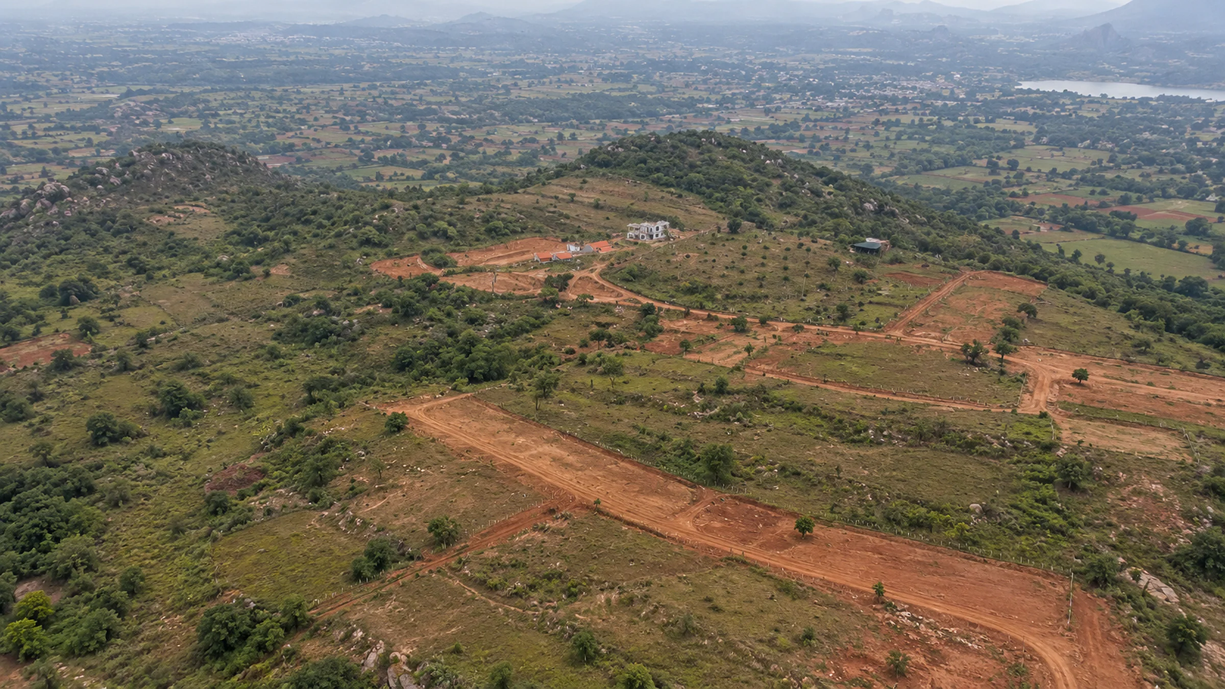 Skyearth from the air: plots and red earth tracks round the house, the boulder hill behind, the valley and reservoir in the haze